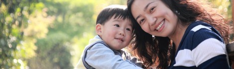 chinese boy with his mom smiling in park